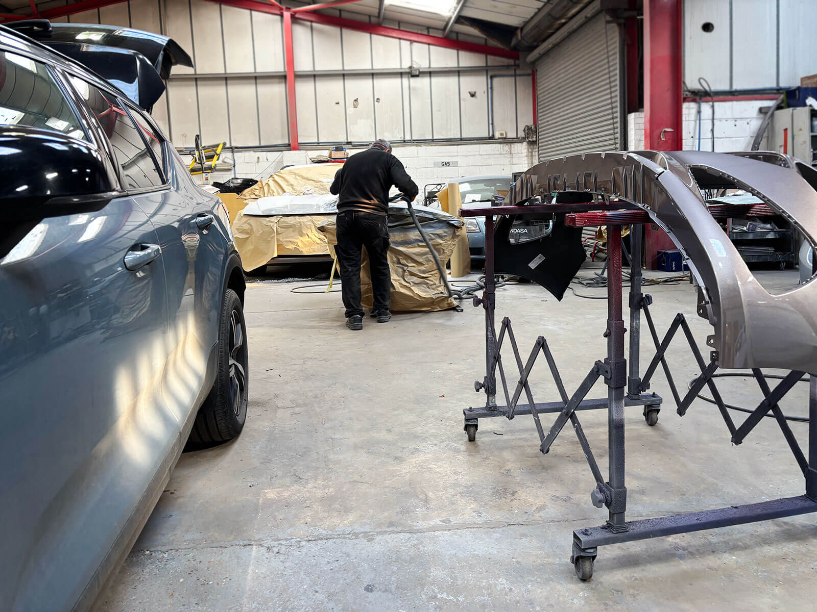 Technician working on a car bodywork repair inside the CARS workshop, Heathfield, East Sussex