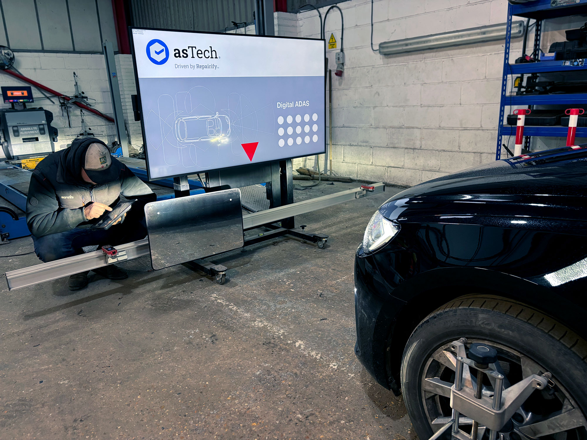 Technician using asTech Digital ADAS calibration equipment on a car after bodywork repair