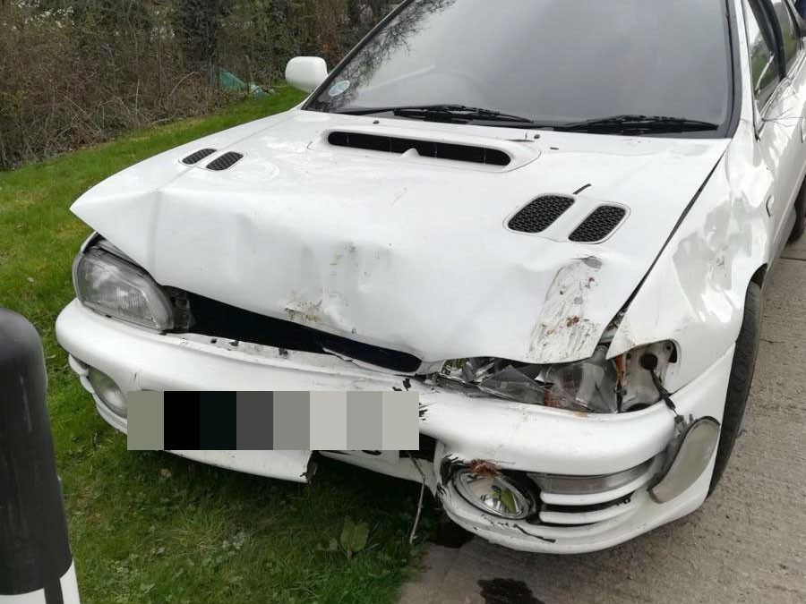 Crumpled bonnet and smashed front bumper on a white Subaru Impreza after a collision