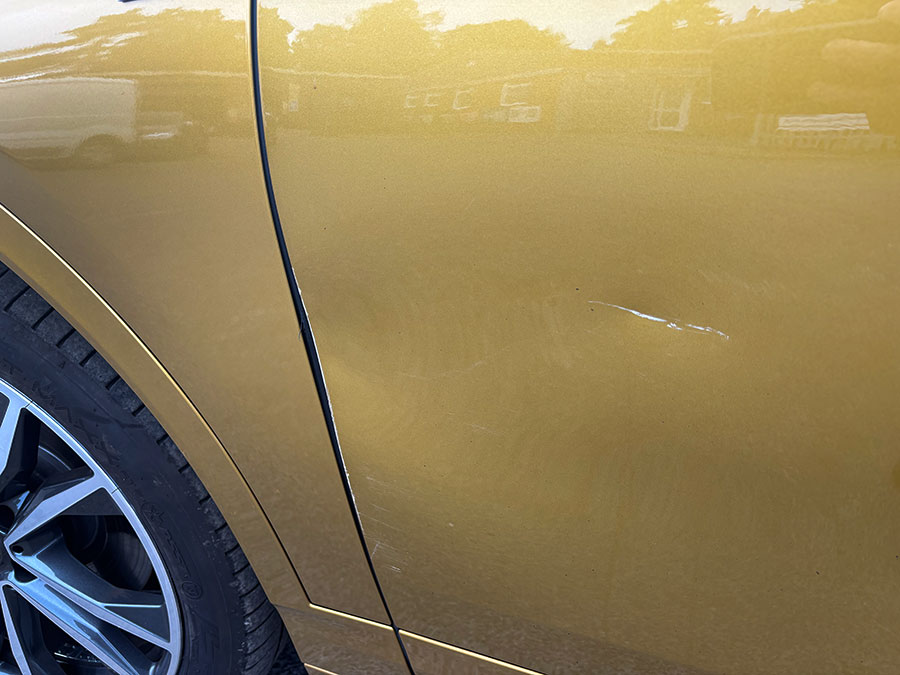 Paint scratch on a gold car door panel ready for colour-matched respray